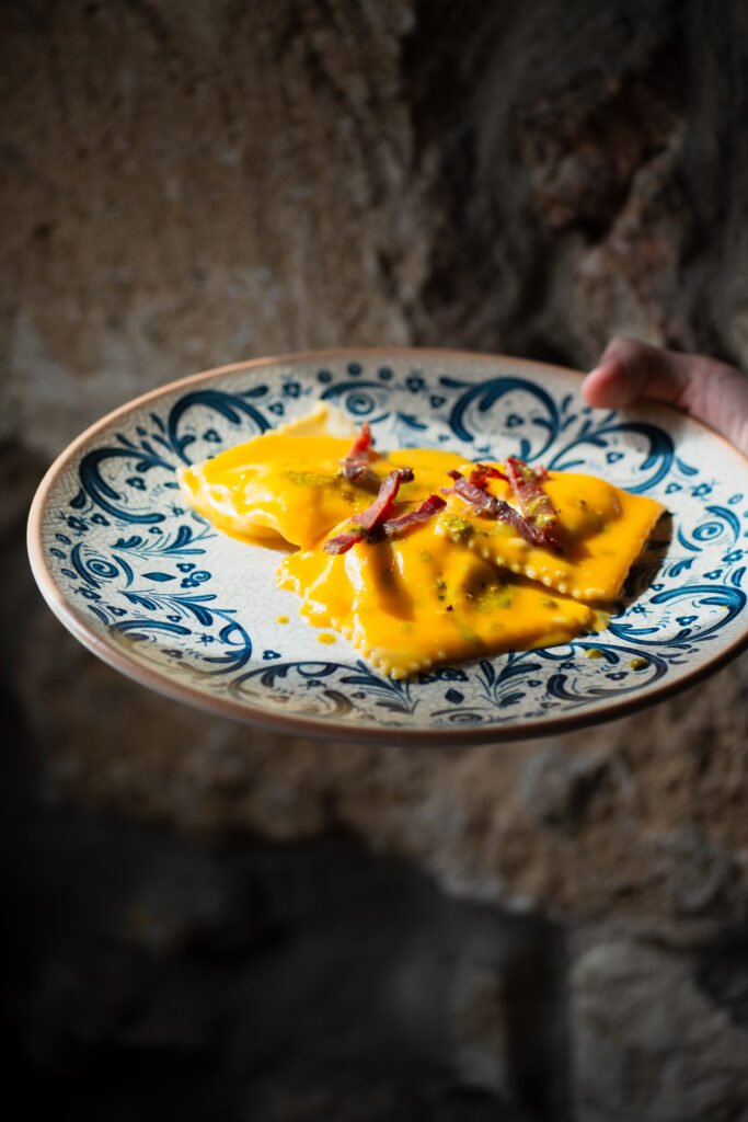 Ravioli artigianali con crema di zucca e guanciale croccante, piatto della tradizione rivisitato, servito in un ristorante in Sicilia.