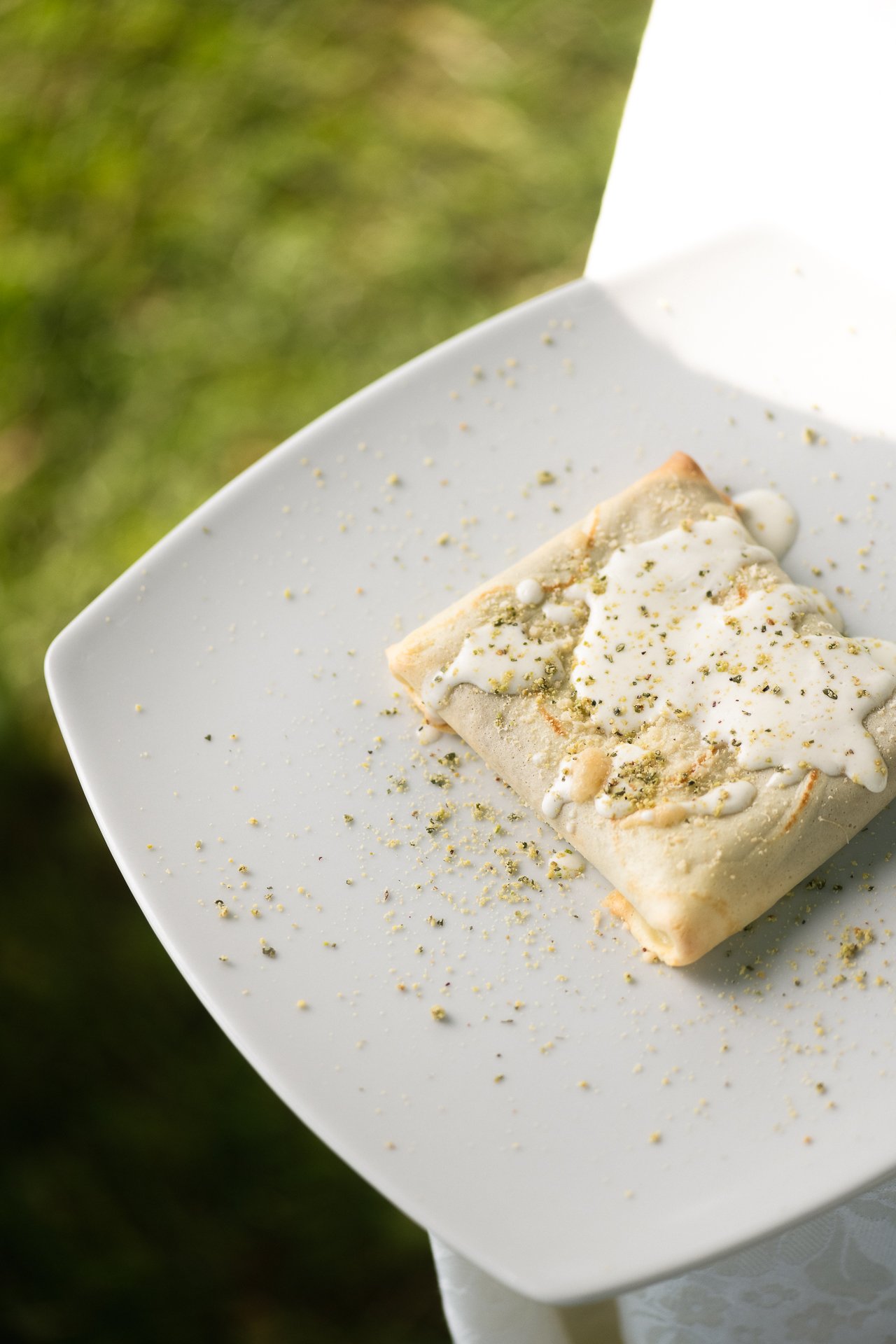 Sfoglia di formaggio con pistacchio servita su tavola in giardino - food photography per agriturismi in Sicilia