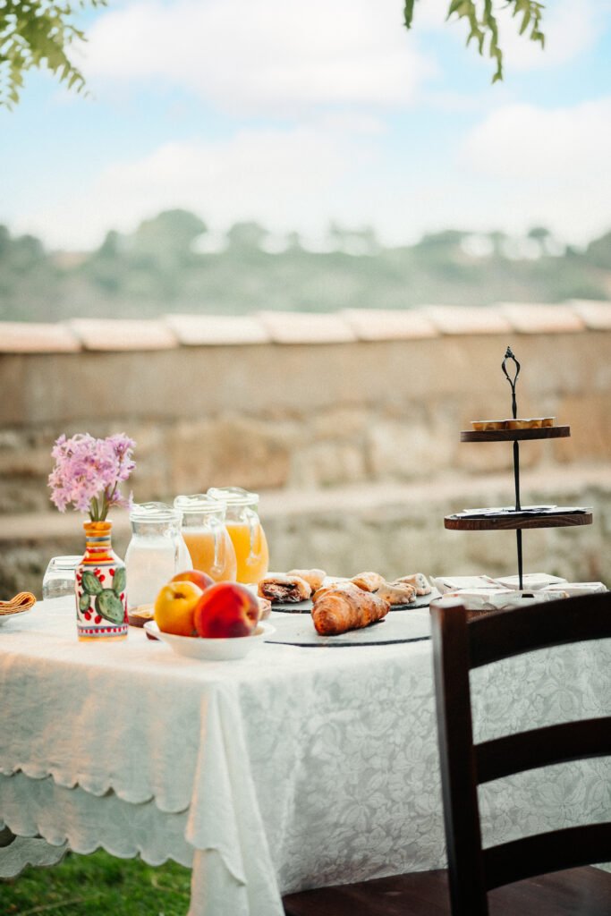 Colazione in giardino di un agriturismo siciliano con croissant, succhi e frutta - fotografia alimentare di Andrea Ventura