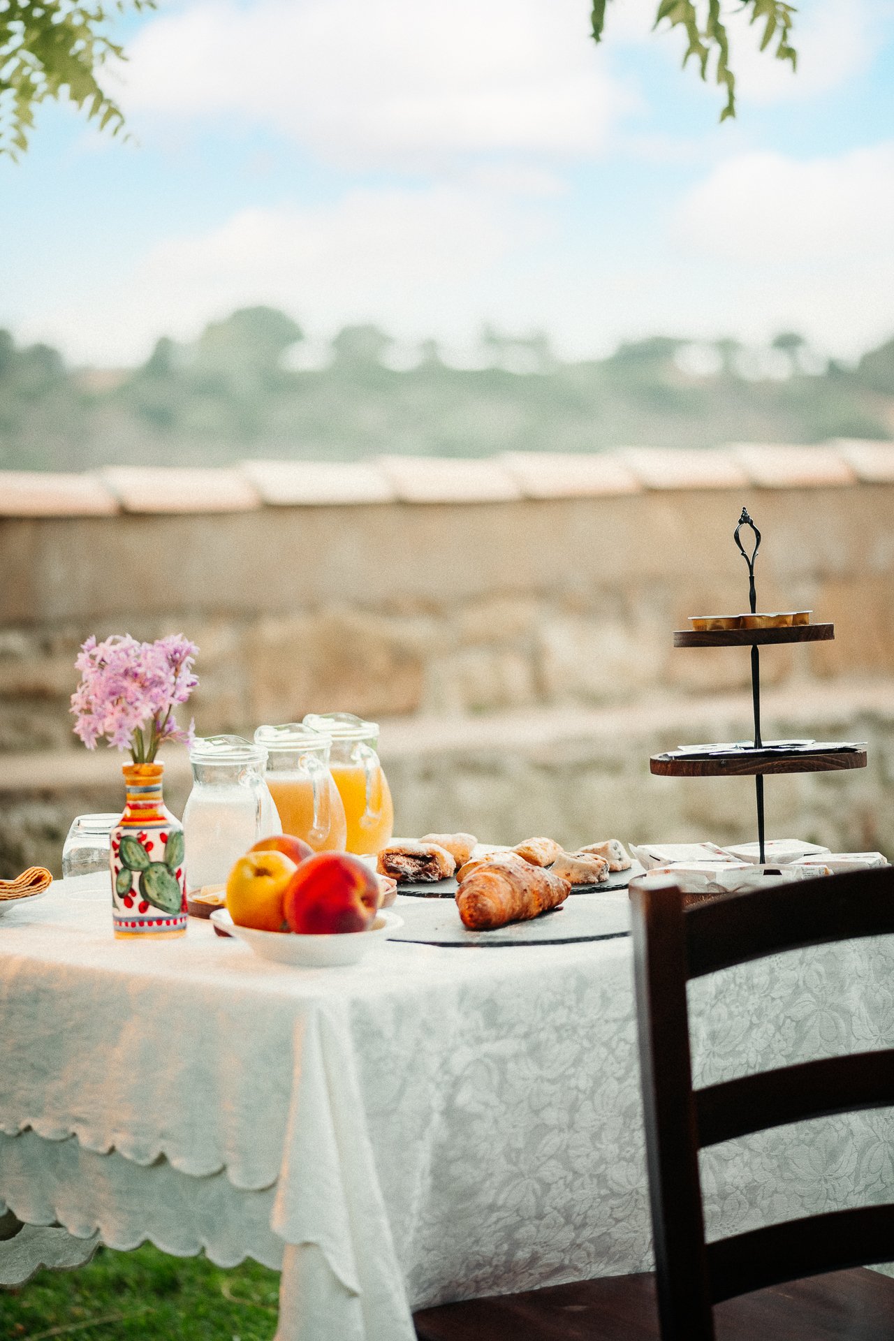 Colazione in giardino di un agriturismo siciliano con croissant, succhi e frutta - fotografia alimentare di Andrea Ventura