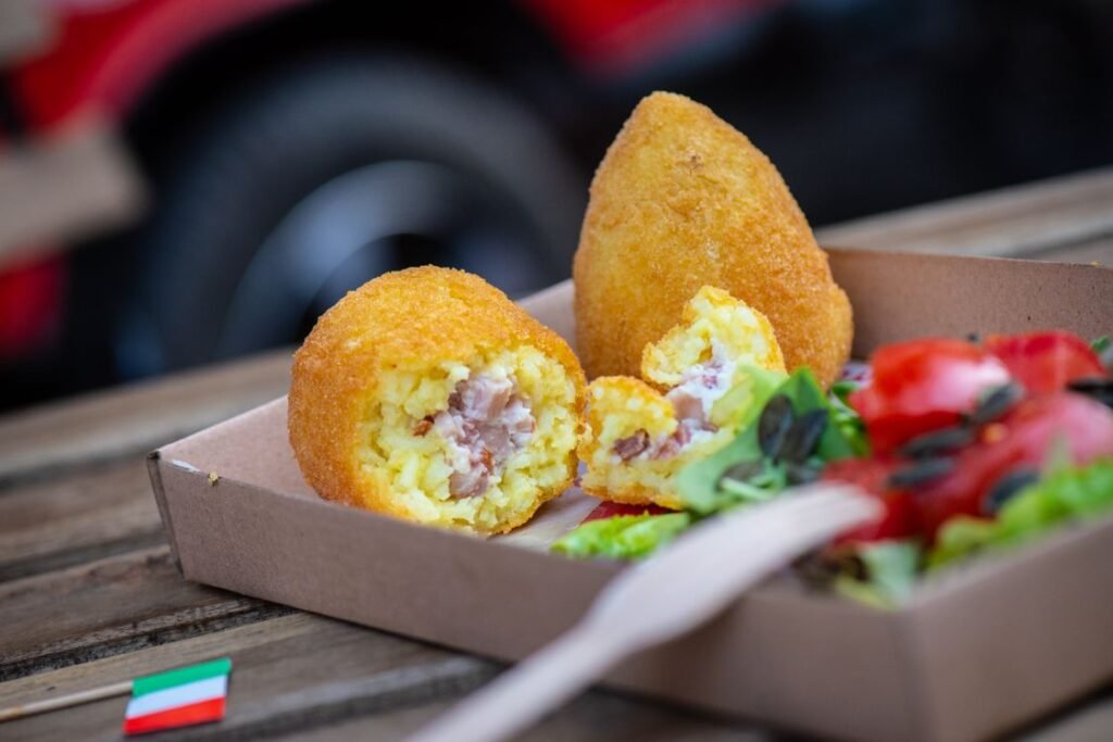 Arancini siciliani in una scatola con insalata