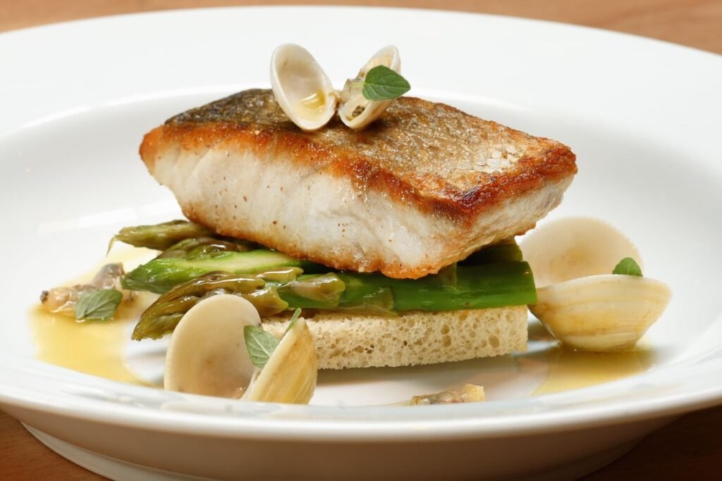 Piatto di pesce con vongole e asparagi, impiattamento da ristorante stellato