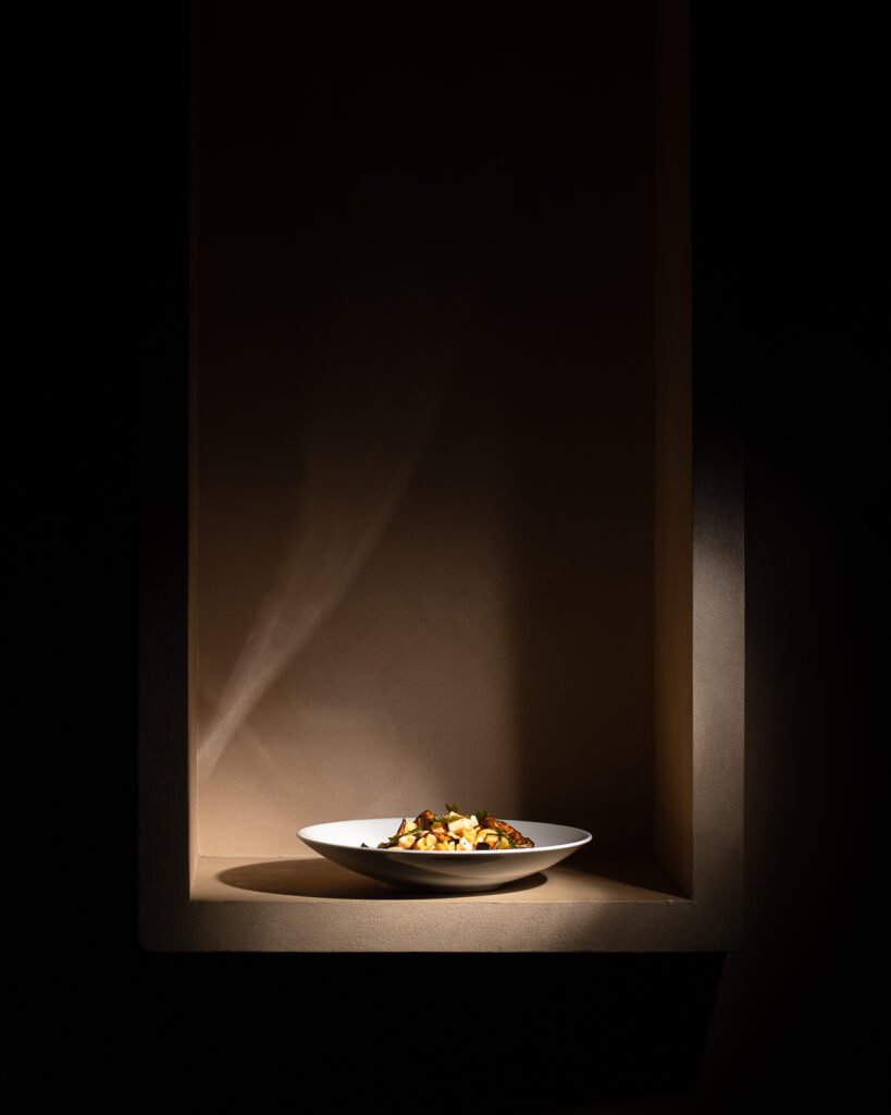 Piatto illuminato da un fascio di luce in una nicchia scura, fotografia food editoriale