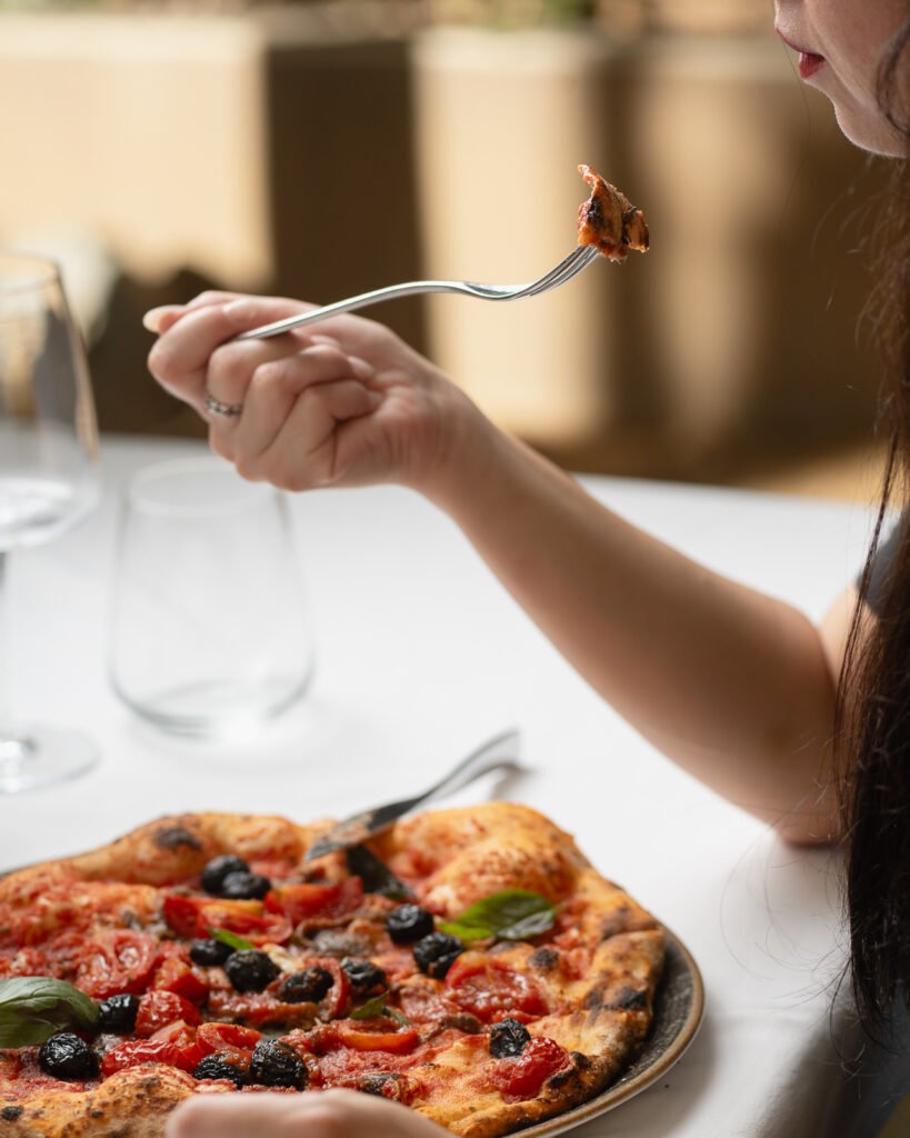 Cliente che mangia una pizza all'aperto in un ristorante siciliano